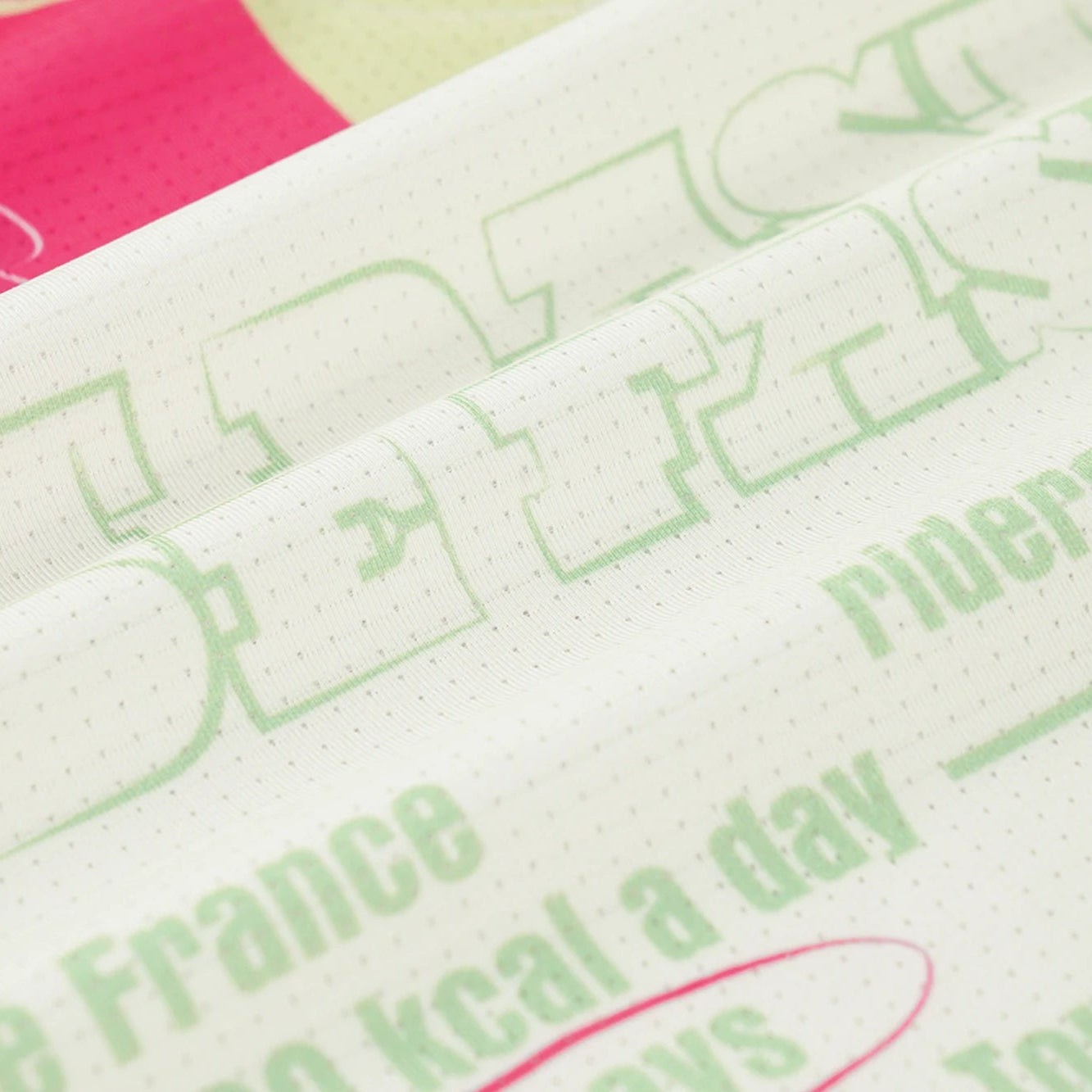 Close-up of a fabric with printed text and logos, including 'Riders' and 'De France'.
