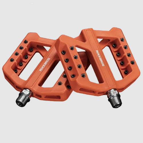 Orange bicycle pedals with text detailing features on a dark background