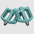 Pair of teal bicycle pedals with threaded ends on a light gray background