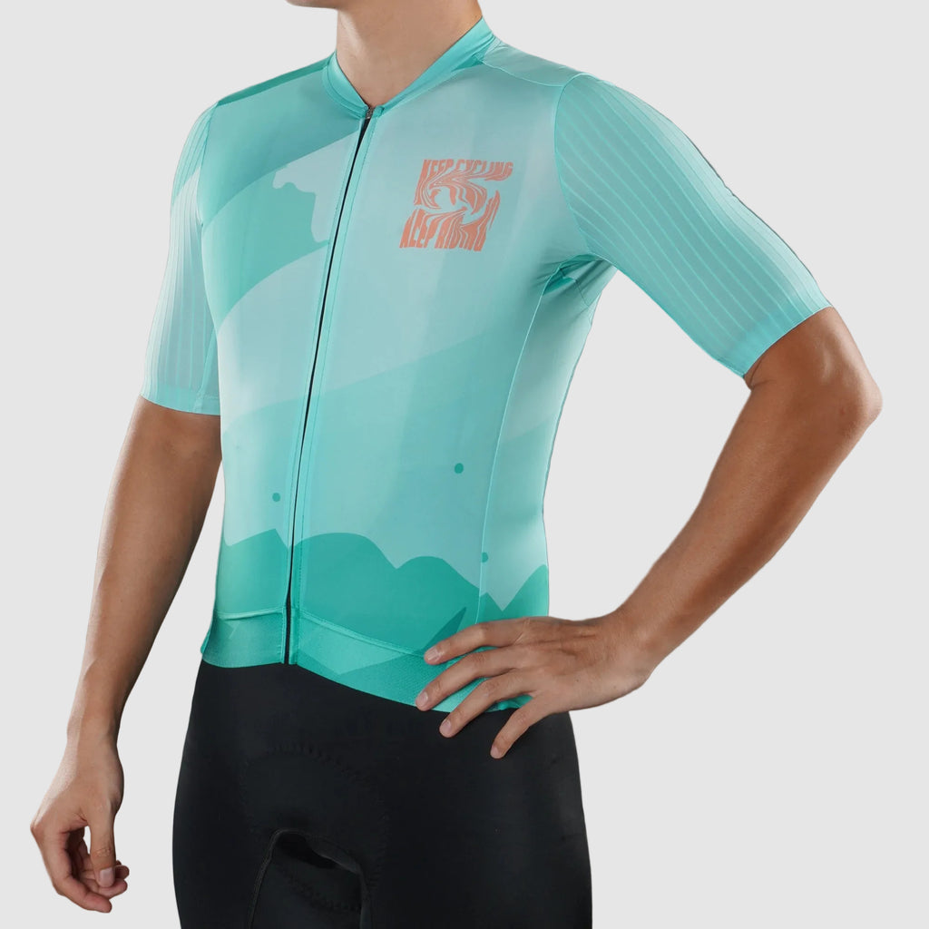 Person wearing a teal cycling jersey with a logo on a gray background