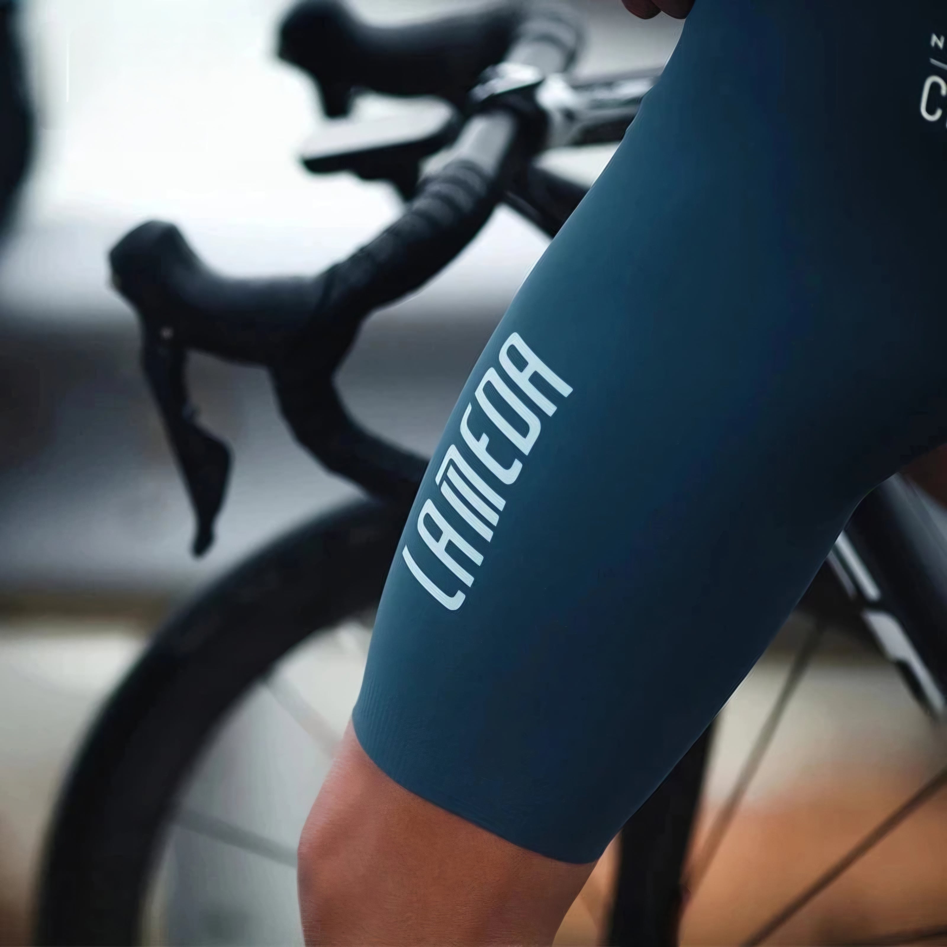 Blue arm sleeve with 'CAMEO' branding on a blurred bicycle background
