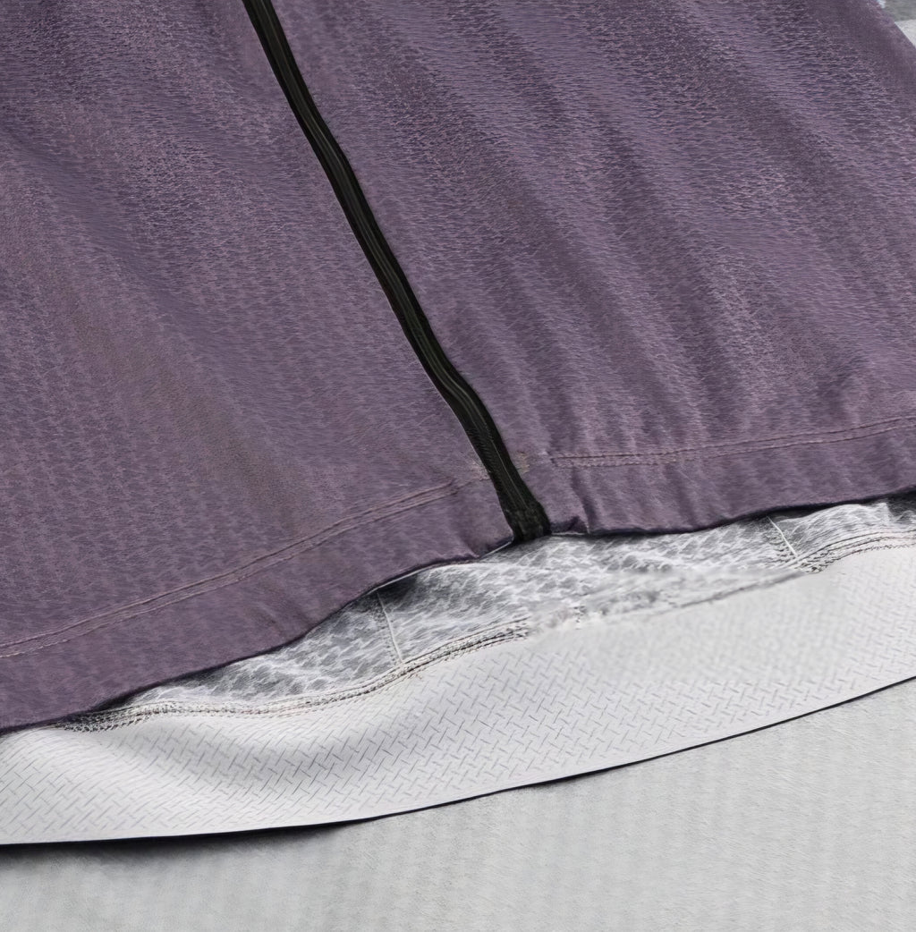 Close-up of a purple garment with a zipper and gray lining.